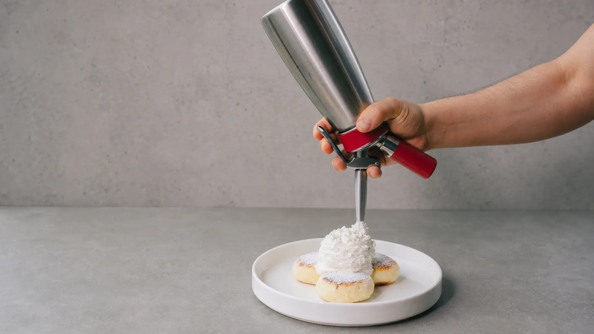 Cross-section diagram of a whipped cream dispenser showing charger, gas headspace, and cream inside